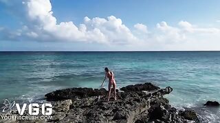 A petite girl is naked on the beach and caresses her body
