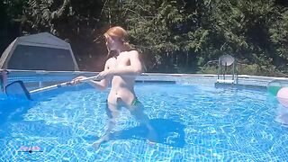 Redhead in red bikini, ignoring her partner while tanning by the pool