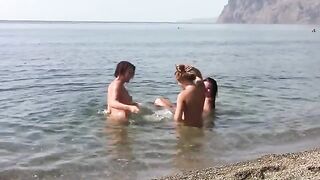 Three naked beauties on the coast of a public beach
