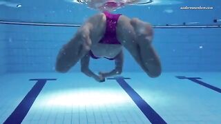 A naked girl is swimming in the pool with an underwater camera
