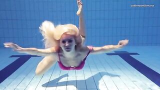 A naked girl is swimming in the pool with an underwater camera