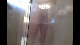 A man washes himself in the shower, unaware of being watched