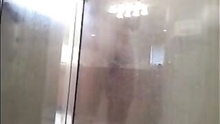A man washes himself in the shower, unaware of being watched