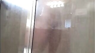 A man washes himself in the shower, unaware of being watched