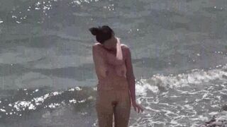 A couple of free-spirited nudists enjoy each other on the beach