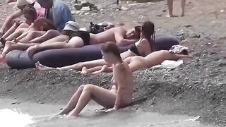 A couple of free-spirited nudists enjoy each other on the beach