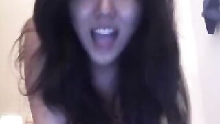 A pretty Asian woman plays with her pussy using a toy on the bed