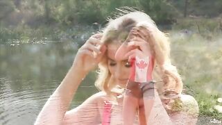 A sexy blonde girl caresses herself on the shores of the lake