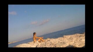 A girl sunbathes naked on the beach, it's a real joy